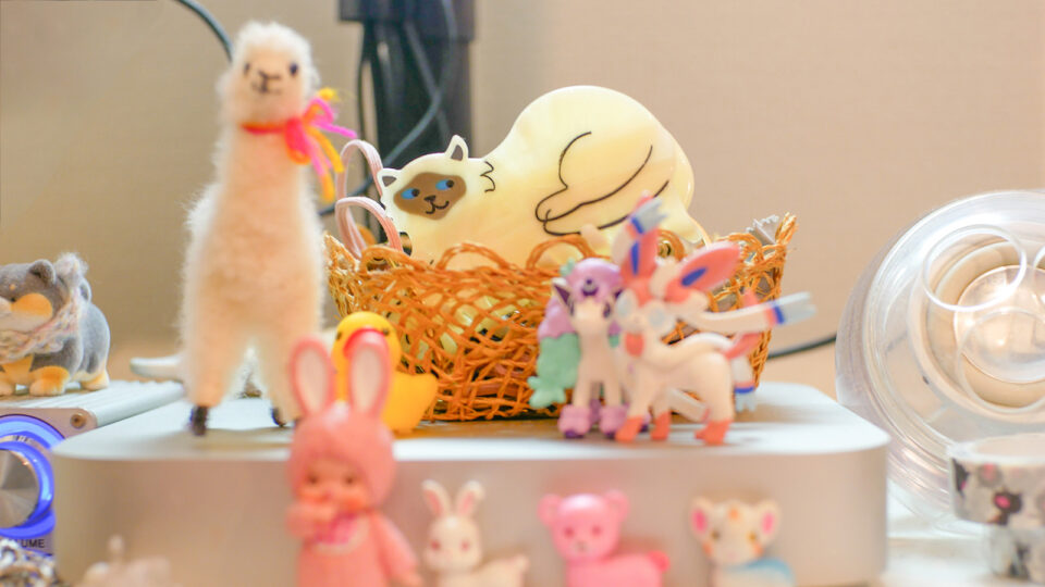 デスクの周りの小物の写真。小さなマスコットがたくさん並ぶ中に溶け込むククシュゼットの猫型のバレッタ。