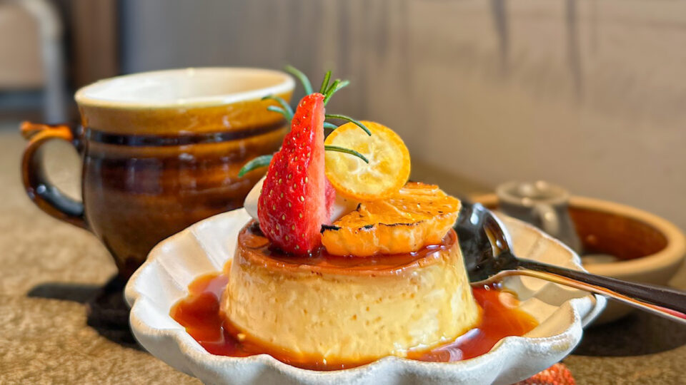 出西窯のカップと季節のフルーツが添えられたプリン。カフェの窓際の、陽がよく当たる席。